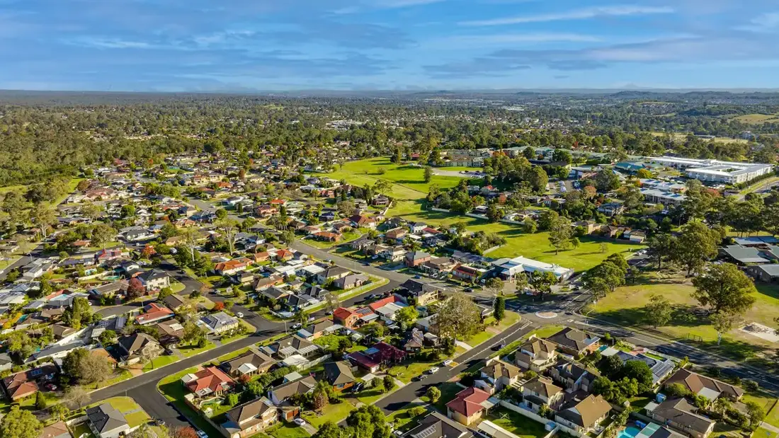 Aerial view of an established Australian suburb of detached homes bordering green parkland
