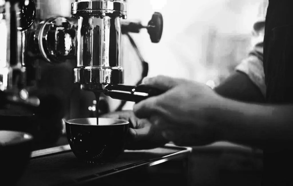 A barista pulling a shot of espresso at a cafe machine