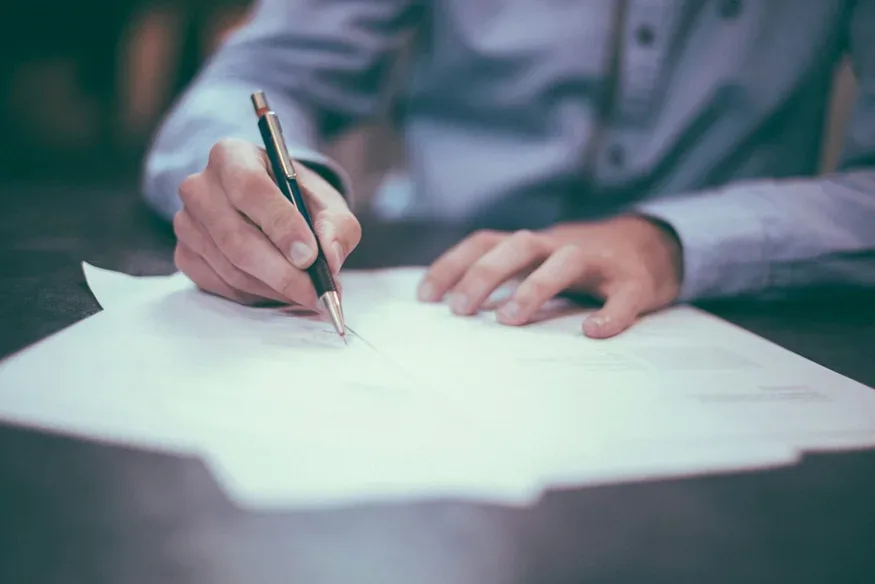 Person signing a property contract at a desk Person signing a property contract at a desk