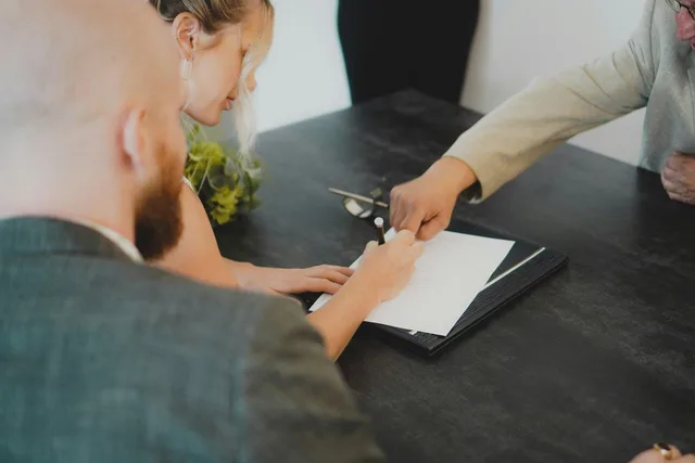 A couple signing a property contract, the point at which the 12 May 2026 negative gearing cutoff is measured.