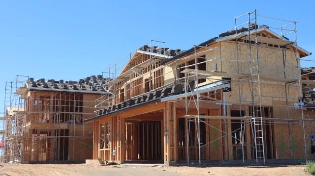 Two-storey houses under construction with exposed timber framing and scaffolding