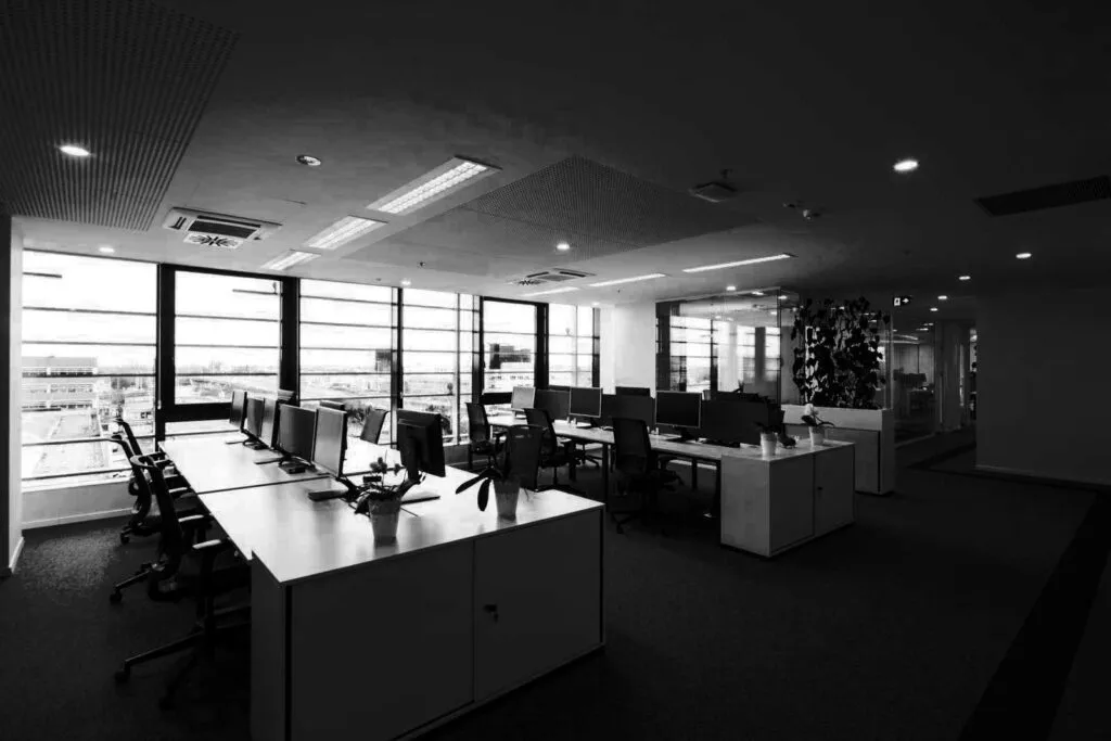 Empty open-plan office with rows of desks and chairs by the windows