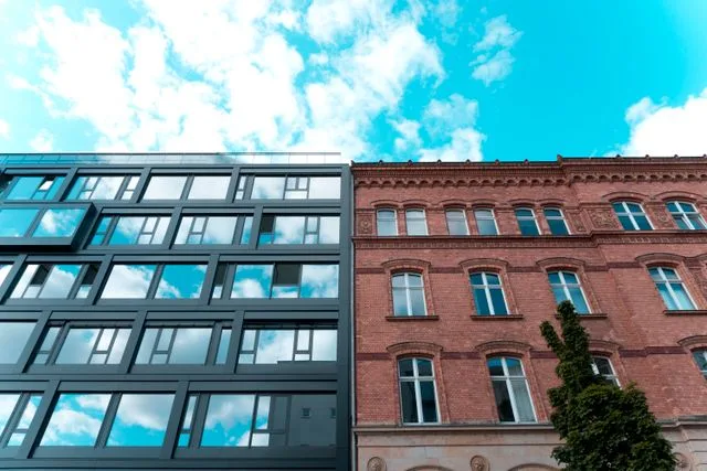 Modern glass building beside an older brick building, new versus established construction