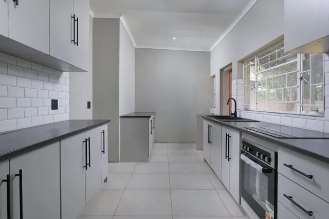 Investment property kitchen showing oven, cabinetry and tiled flooring