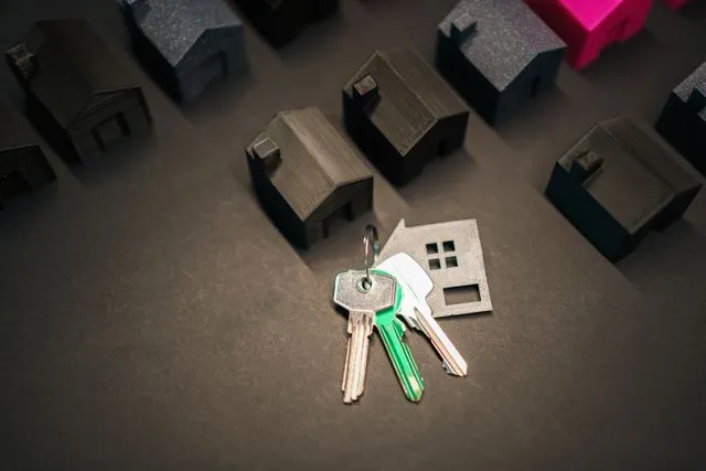 A house-shaped keyring with keys resting in front of a row of miniature model houses