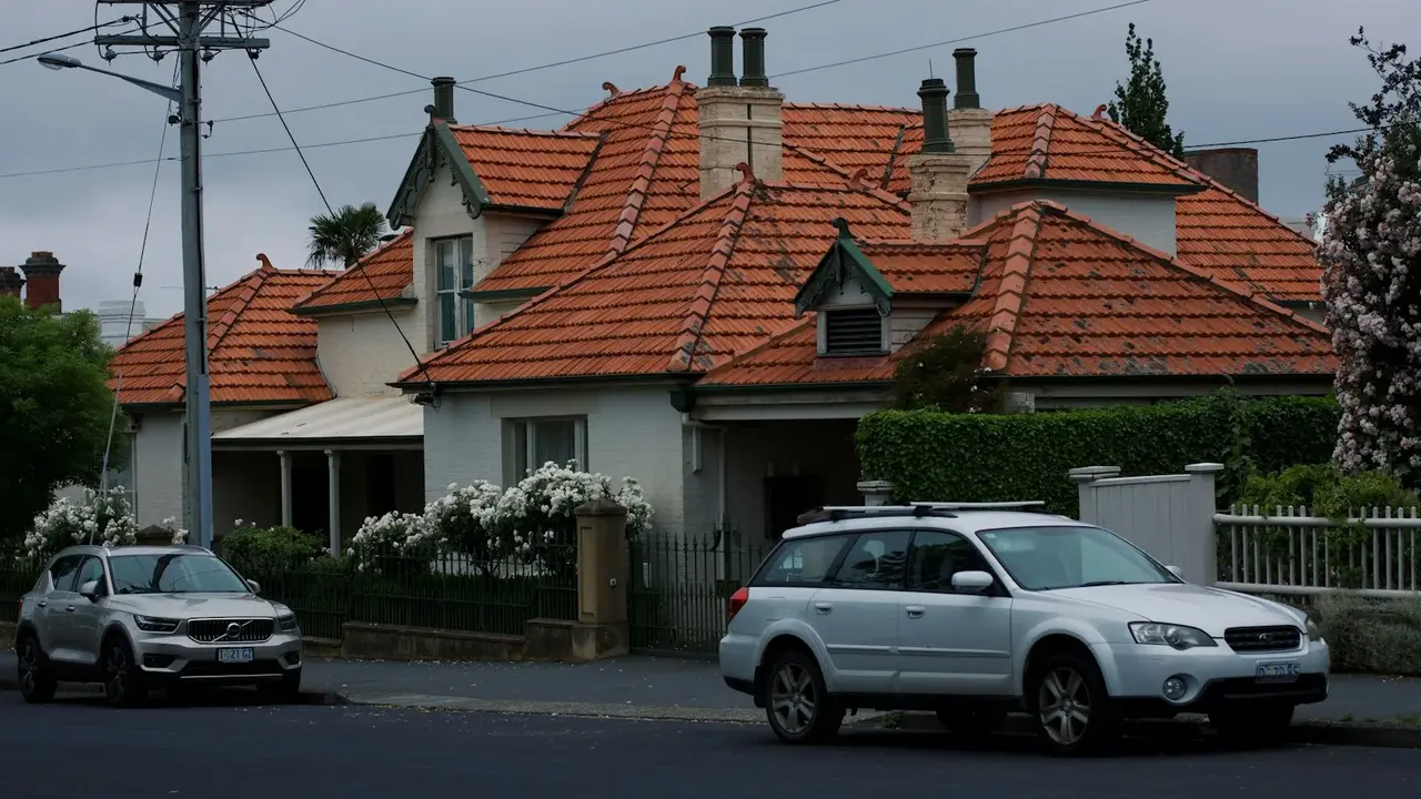 Federation-style house with a terracotta tiled roof and cars parked out the front Federation-style house with a terracotta tiled roof and cars parked out the front