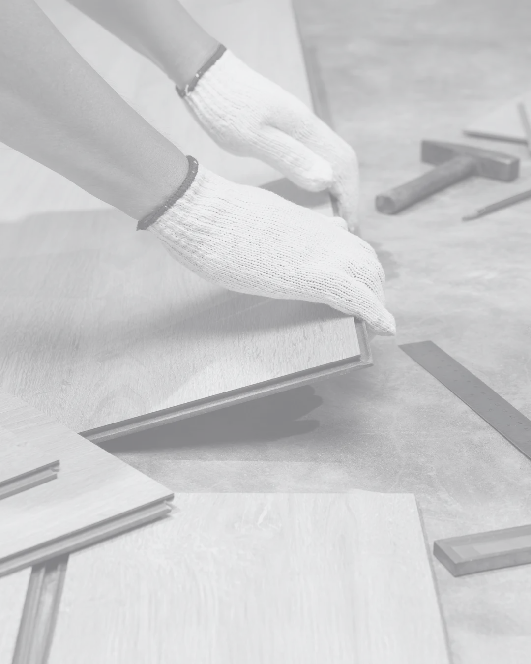 Gloved hands laying timber-look floorboards during a renovation