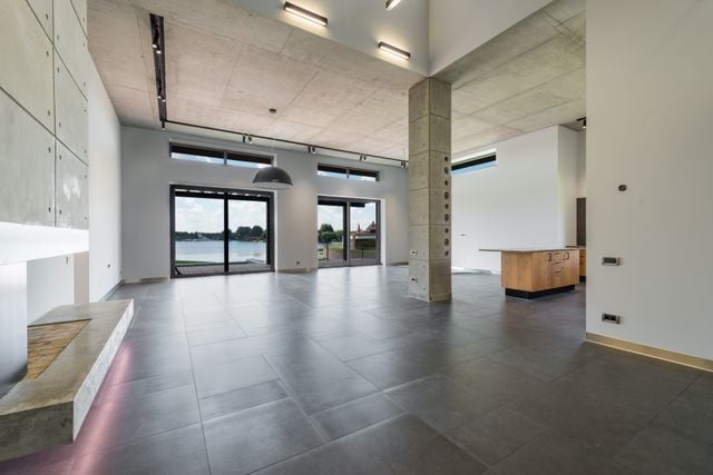Independent Property Valuations: CGT, SMSF and stamp duty explained » independent property valuation Open-plan living area with polished concrete floors, high ceilings and a lake view through floor-to-ceiling windows