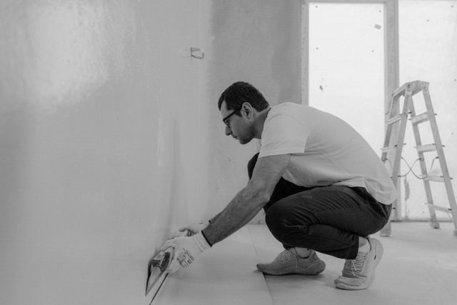 Renovating an investment property? The deductions you could miss out on (scrapping explained) » investment property renovation Tradesperson skim-coating an interior wall during a property renovation